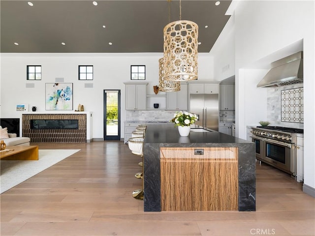 kitchen with a center island, decorative backsplash, wall chimney exhaust hood, and premium appliances