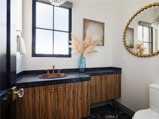 bathroom with an inviting chandelier, vanity, and toilet