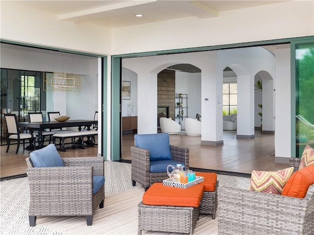 interior space with beam ceiling, a healthy amount of sunlight, and hardwood / wood-style flooring