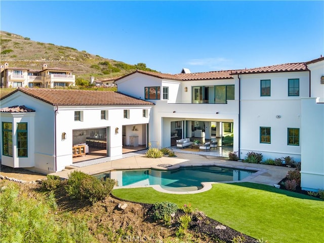 rear view of property with a yard, a patio area, an outdoor hangout area, and a mountain view