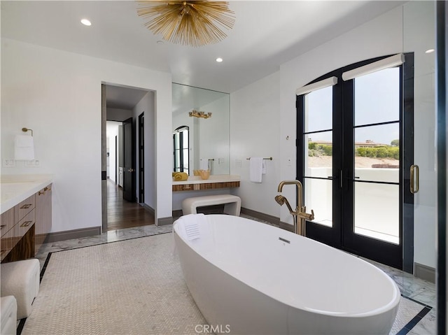 bathroom featuring a washtub, french doors, and vanity