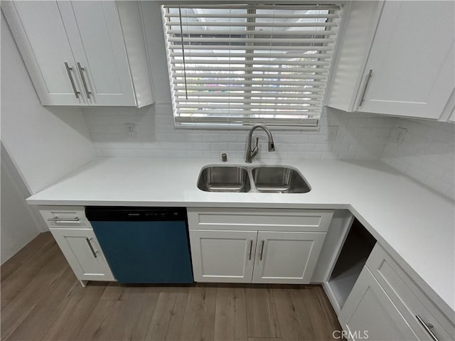 kitchen featuring dark wood-type flooring, dishwashing machine, backsplash, white cabinetry, and sink