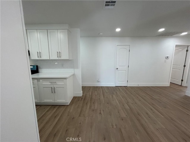 interior space featuring white cabinets, light wood-type flooring, and decorative backsplash