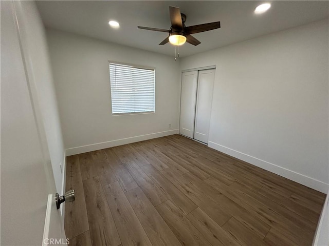 unfurnished bedroom with wood-type flooring, a closet, and ceiling fan