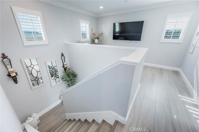 stairway with ornamental molding and hardwood / wood-style flooring