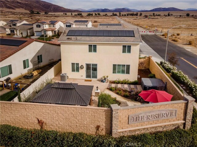 back of property with solar panels, cooling unit, and a mountain view