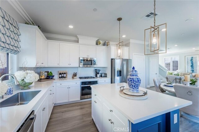 kitchen featuring white cabinets, a kitchen island, stainless steel appliances, sink, and light wood-type flooring