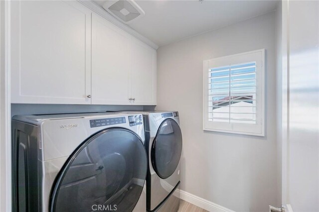 laundry room featuring washer and clothes dryer, light hardwood / wood-style flooring, and cabinets