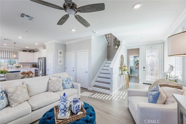 living room featuring ceiling fan, ornamental molding, and light wood-type flooring