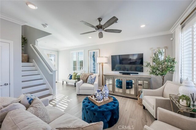 living room featuring ceiling fan, ornamental molding, and light hardwood / wood-style floors