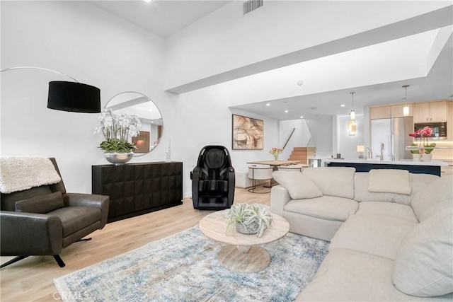 living room with light wood-type flooring and a towering ceiling