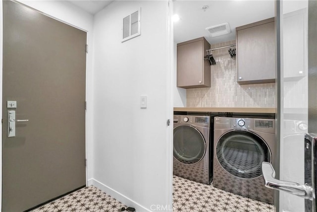 clothes washing area featuring cabinets and washing machine and clothes dryer