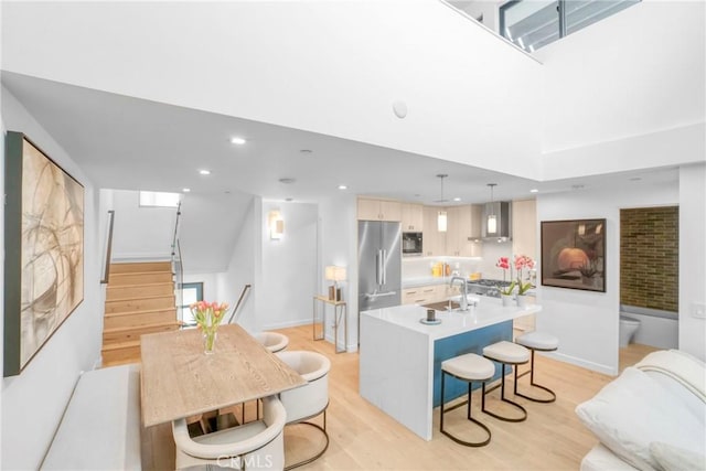 kitchen featuring decorative light fixtures, a center island with sink, light wood-type flooring, and high end refrigerator