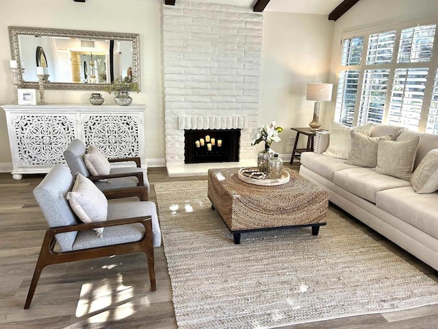 living room with beam ceiling, wood-type flooring, and a brick fireplace