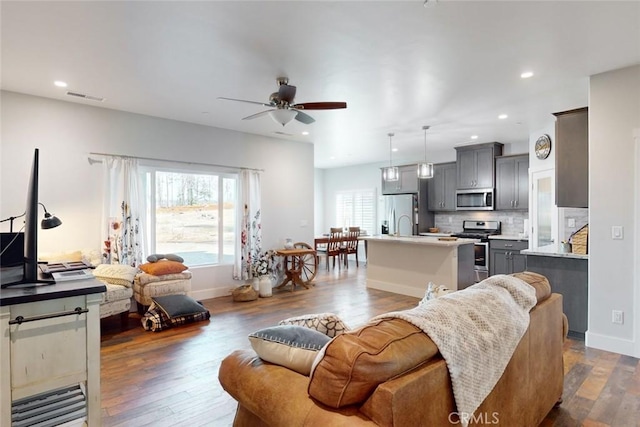 living room with ceiling fan and dark hardwood / wood-style flooring