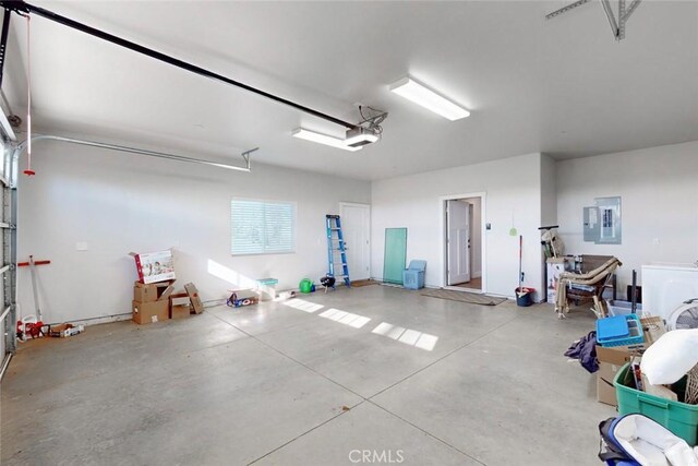 garage featuring a garage door opener, washer / dryer, and electric panel