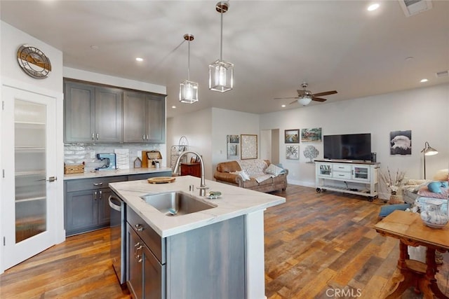 kitchen featuring sink, a kitchen island with sink, tasteful backsplash, dark hardwood / wood-style flooring, and decorative light fixtures