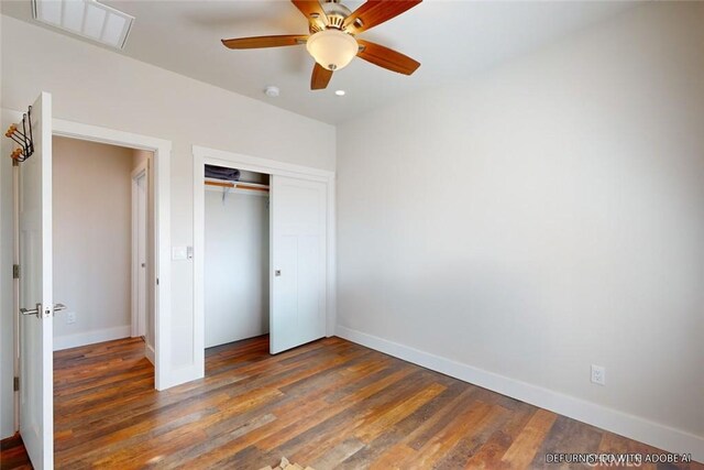 unfurnished bedroom featuring dark wood-type flooring, ceiling fan, and a closet