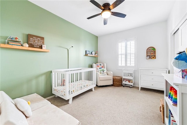 bedroom with ceiling fan, carpet floors, and a crib