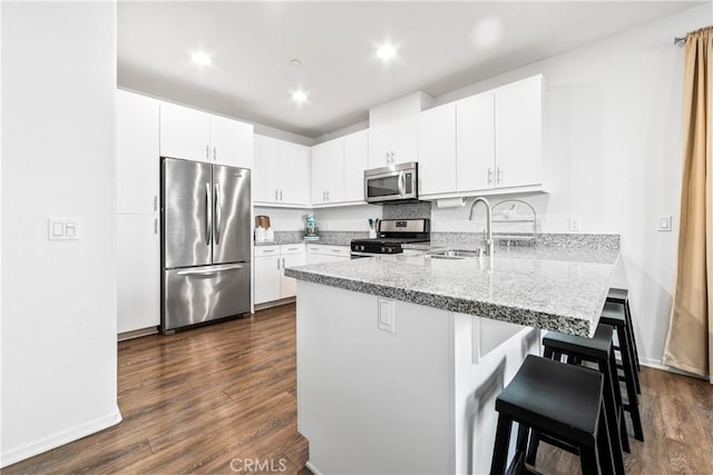 kitchen featuring sink, dark wood-type flooring, a breakfast bar area, stainless steel appliances, and white cabinets