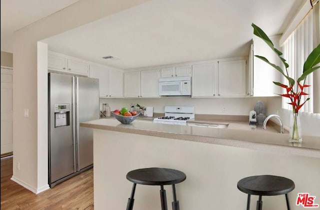 kitchen with stove, white cabinetry, stainless steel fridge with ice dispenser, and kitchen peninsula