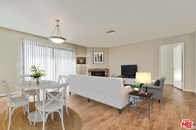 living room with a brick fireplace and light hardwood / wood-style flooring