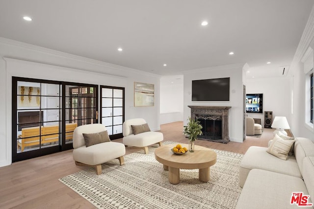 living room featuring a high end fireplace, crown molding, and light hardwood / wood-style flooring