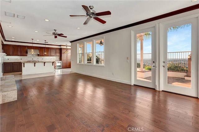 unfurnished living room featuring ornamental molding, dark hardwood / wood-style flooring, and ceiling fan