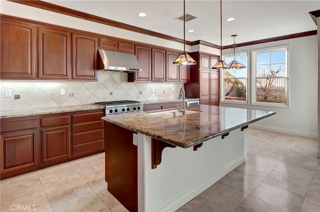 kitchen featuring sink, decorative light fixtures, stone countertops, wall chimney range hood, and a kitchen island with sink