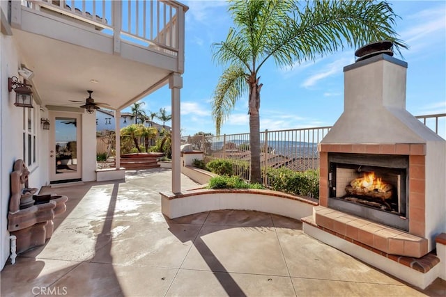 view of patio with a tile fireplace and a balcony