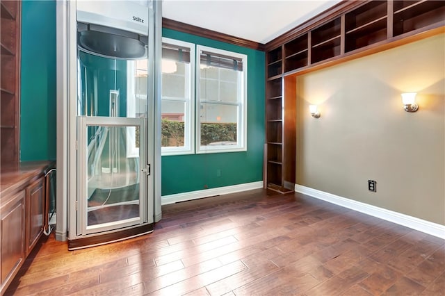 unfurnished room with ornamental molding and dark wood-type flooring