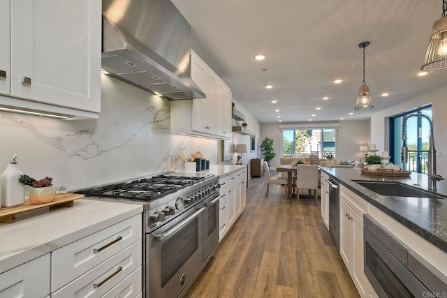 kitchen featuring stainless steel appliances, white cabinetry, decorative light fixtures, exhaust hood, and tasteful backsplash