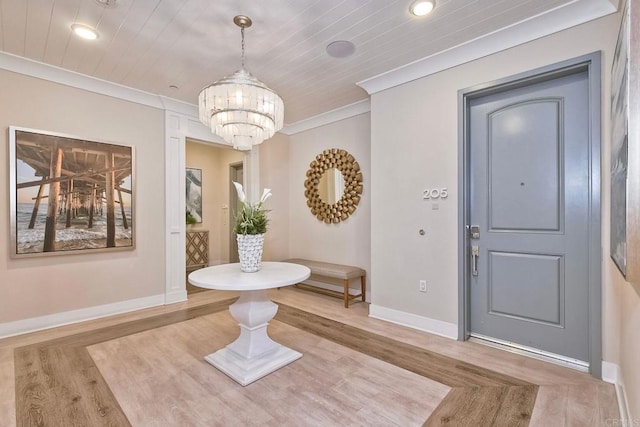 entryway with an inviting chandelier, ornamental molding, and wood-type flooring