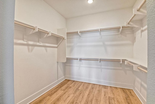 walk in closet with light hardwood / wood-style floors