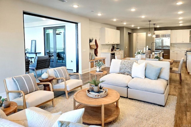 living room with sink, beverage cooler, and light hardwood / wood-style flooring