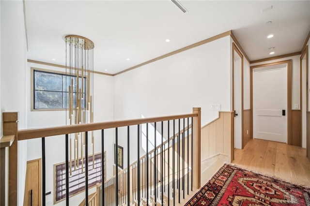 hallway with light wood-type flooring and crown molding