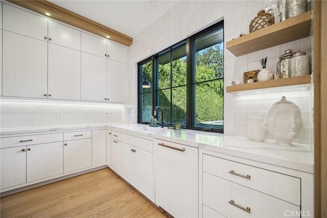 kitchen featuring sink, white cabinets, light hardwood / wood-style floors, and tasteful backsplash