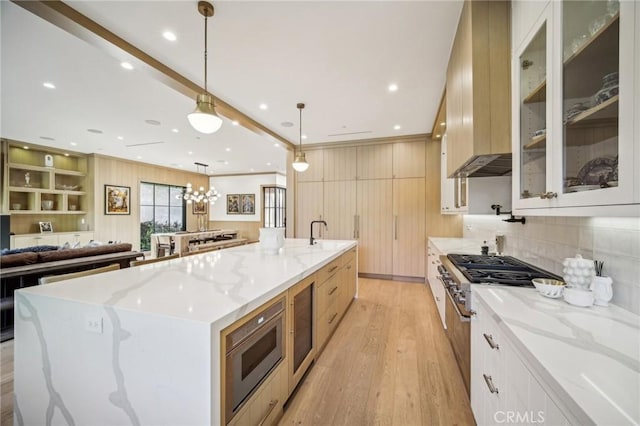 kitchen with light hardwood / wood-style floors, hanging light fixtures, a large island, and light stone countertops