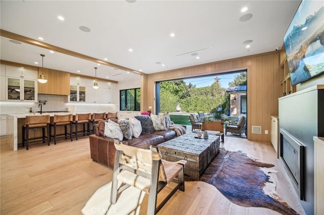 living room featuring light wood-type flooring and beamed ceiling