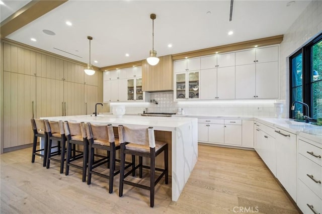 kitchen featuring decorative light fixtures, white cabinets, and a large island