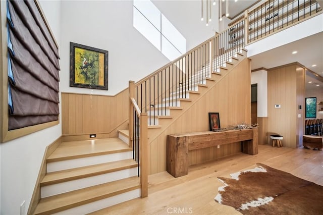 stairway featuring a high ceiling, wooden walls, and wood-type flooring