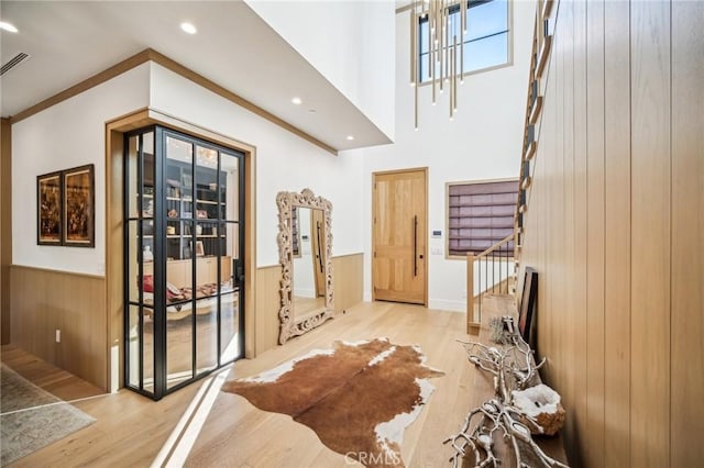 entryway featuring wood walls, ornamental molding, and light wood-type flooring