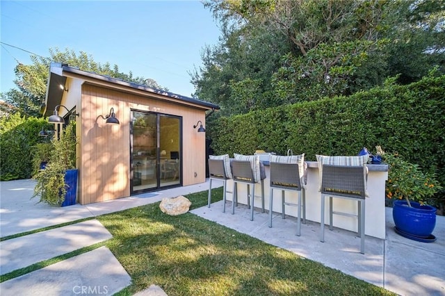 rear view of house with an outdoor bar and a lawn