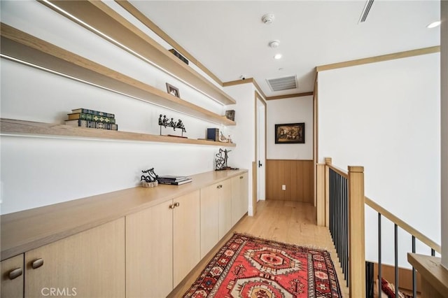 interior space with crown molding, wood walls, and light hardwood / wood-style floors