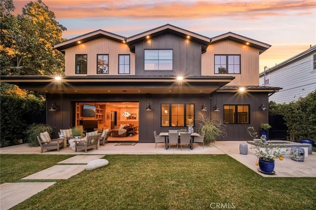 back house at dusk featuring a patio area, outdoor lounge area, and a yard