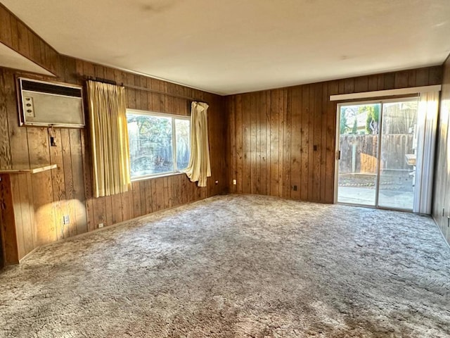 empty room with plenty of natural light, an AC wall unit, wooden walls, and carpet