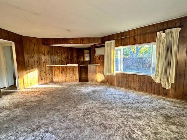 unfurnished living room with wooden walls and carpet floors