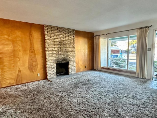 unfurnished living room featuring carpet floors, a fireplace, and wood walls