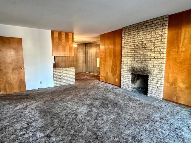 unfurnished living room featuring dark carpet, a fireplace, and wood walls