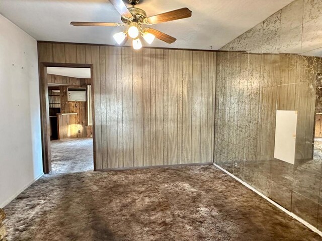 carpeted empty room with ceiling fan and wood walls